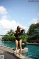 A woman in a black bathing suit standing next to a pool.