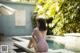 A woman in a pink bathing suit sitting by a pool.