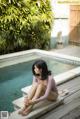 A woman sitting on the edge of a swimming pool.