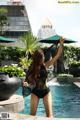 A woman in a black bathing suit standing next to a pool.