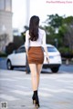 A woman walking down the street in a brown skirt.