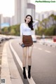 A woman in a white shirt and brown skirt posing for a picture.