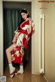 A woman in a red and white kimono leaning against a door.