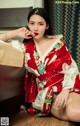 A woman in a red and white kimono sitting on a bed.