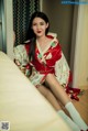 A woman in a red and white kimono sitting on a bed.