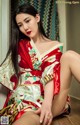 A woman in a red and white kimono sitting on the floor.