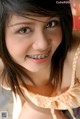 A young woman with braces smiles at the camera.