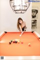 A woman is playing pool in a room.