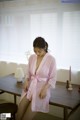 A woman in a pink robe sitting on a table.