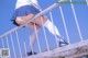 A woman in a school uniform is standing on a railing.