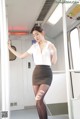 A woman in a white shirt and black skirt on a train.