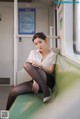 A woman sitting on a train with her legs crossed.