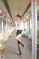 A woman in a white shirt and black skirt on a train.