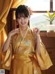 A woman in a yellow kimono standing by a window.