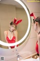 A woman in a red dress is looking at herself in the mirror.