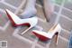 A pair of white and red high heels on a carpeted floor.