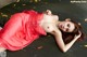 A woman in a red dress laying on a wooden floor.