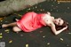 A woman in a red dress laying on a wooden floor.