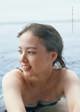 A woman in a blue bikini sitting in the water.