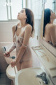 A woman in a white lingerie standing in a bathroom.