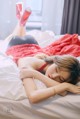 A woman laying on top of a bed in a red dress.