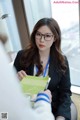 A woman in a business suit sitting at a desk with a book.