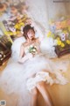 A woman in a wedding dress laying on the floor with flowers.