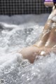 A woman is sitting in a bathtub with foam on her feet.