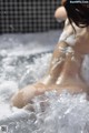 A naked woman sitting in a bathtub filled with foam.