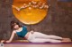 A woman in a blue top and white leggings laying on a yoga mat.