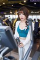 A woman in a blue top and white pants on a treadmill.