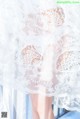 A close up of a woman wearing a white lace dress.