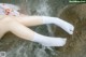 A woman's legs in white socks in the water.