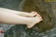 A woman's bare feet in the water of a stream.