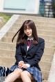 A woman in a school uniform sitting on some steps.