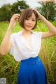 A woman in a white shirt and blue skirt posing for a picture.