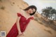 A woman in a red dress standing in the desert.