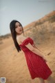 A woman in a red dress standing in the desert.