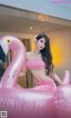 A woman in a pink bikini sitting on an inflatable flamingo.