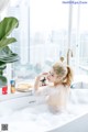 A woman sitting in a bathtub with a plate of food.