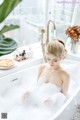 A woman sitting in a bathtub filled with foam.