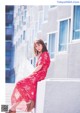 A woman in a red dress sitting on a ledge.