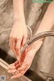 A woman washing her hands under a faucet in a bathroom sink.