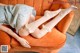 A woman laying on an orange couch wearing white stockings.