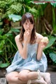 A woman in a blue dress eating a piece of cake.