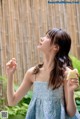 A woman in a blue dress holding a piece of cake.