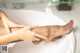 A woman's legs in a bathtub with her hands on her knees.