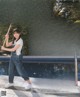 A woman holding a baseball bat in front of a swimming pool.