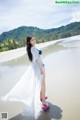 A woman in a white dress standing on a beach.