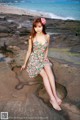 A woman sitting on a rock on the beach.